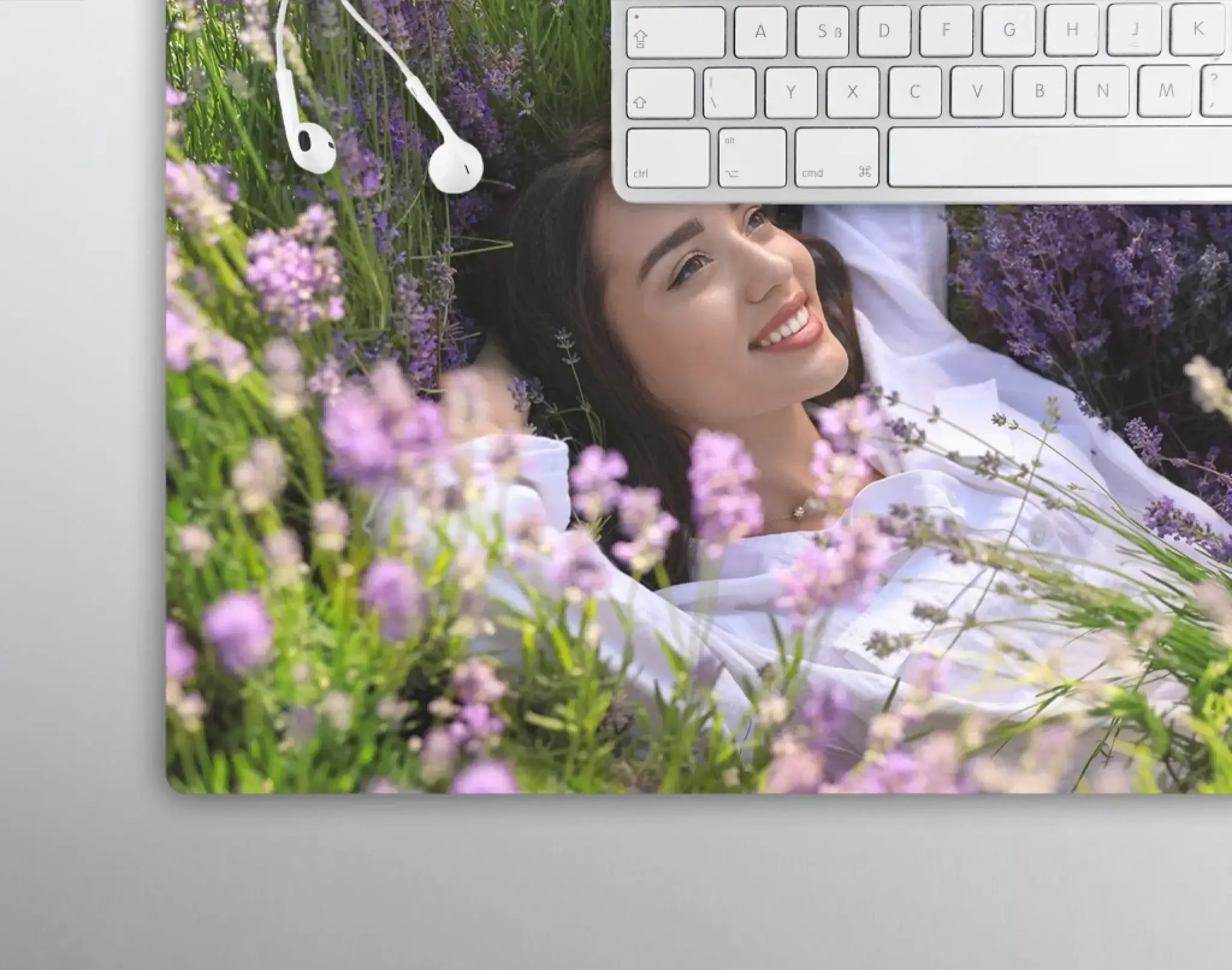 Weiße kabellose earbuds liegen auf tastatur mit lavendelblüten und lächelnder frau im hintergrund zum geburtstag