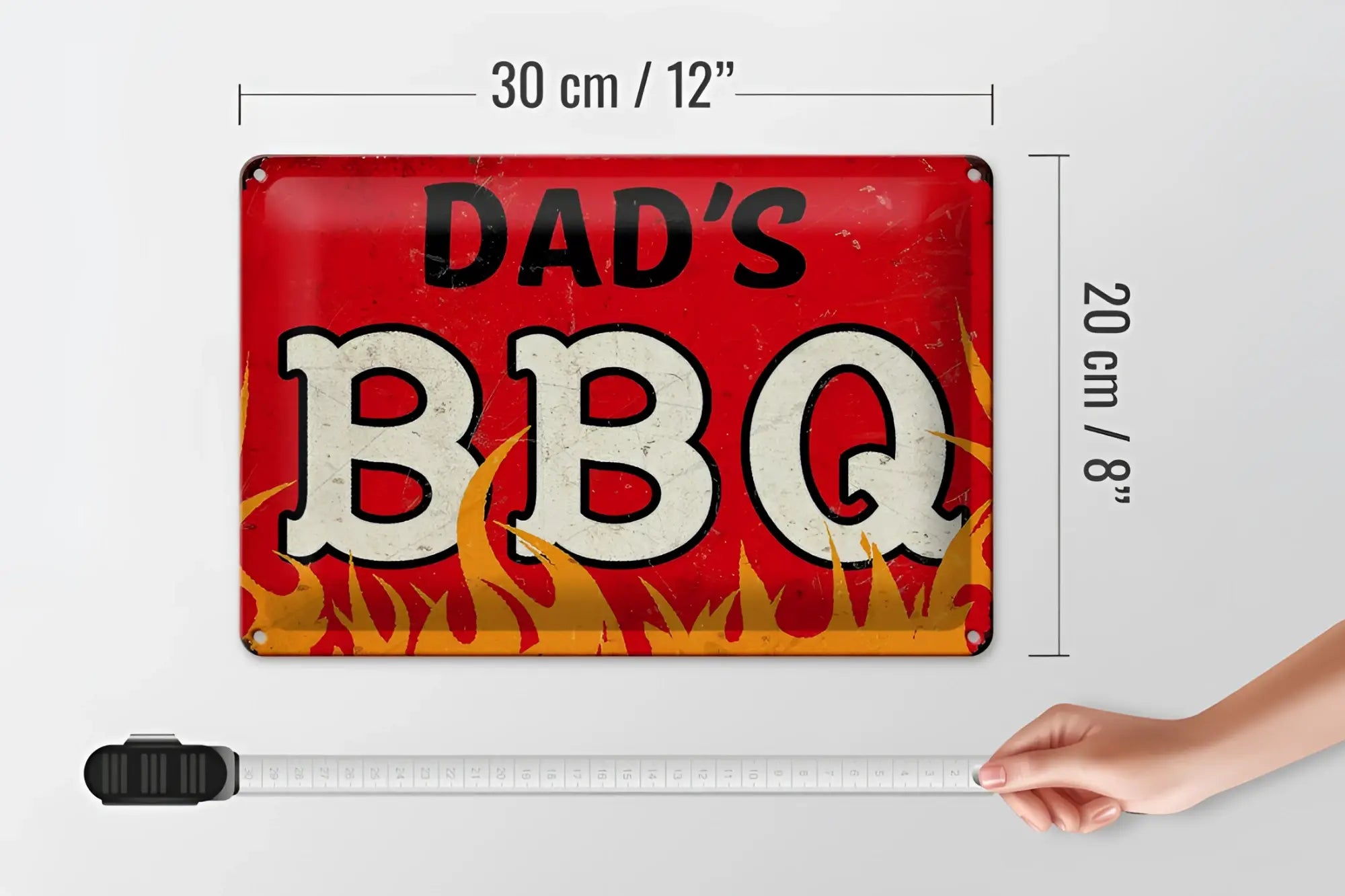 Rotes rechteckiges blechschild dad’s bbq mit abgenutzter weißer und schwarzer schrift und flammengrafik 20x30cm