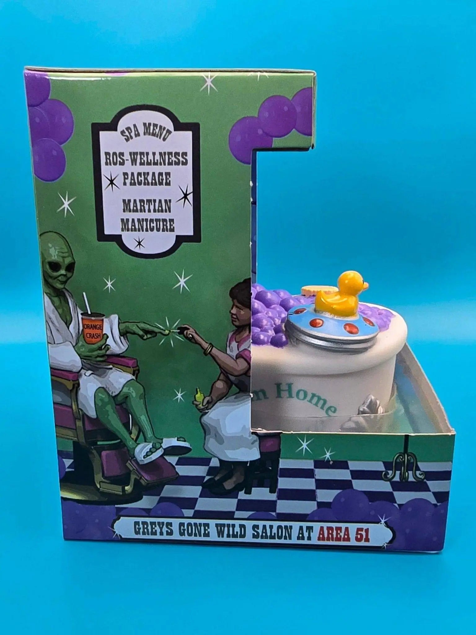 Ein weißes keramik spa mannequin mit gelber gummiente in bunter verpackung von celebriDucks