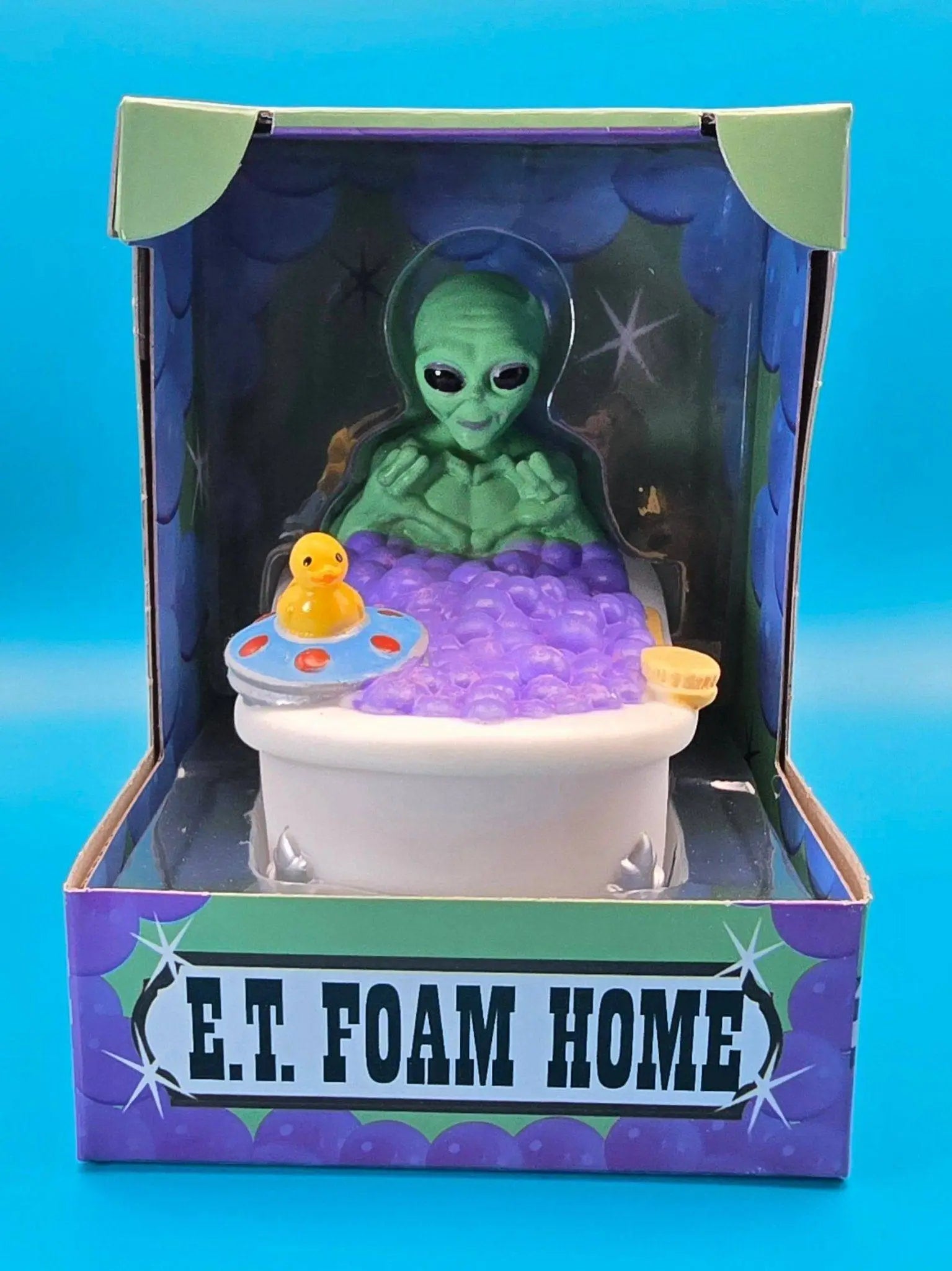 Grüner alien gummiente im weißen bad mit lila schaum gelber badeente und ufovorm spielzeug von celebriducks