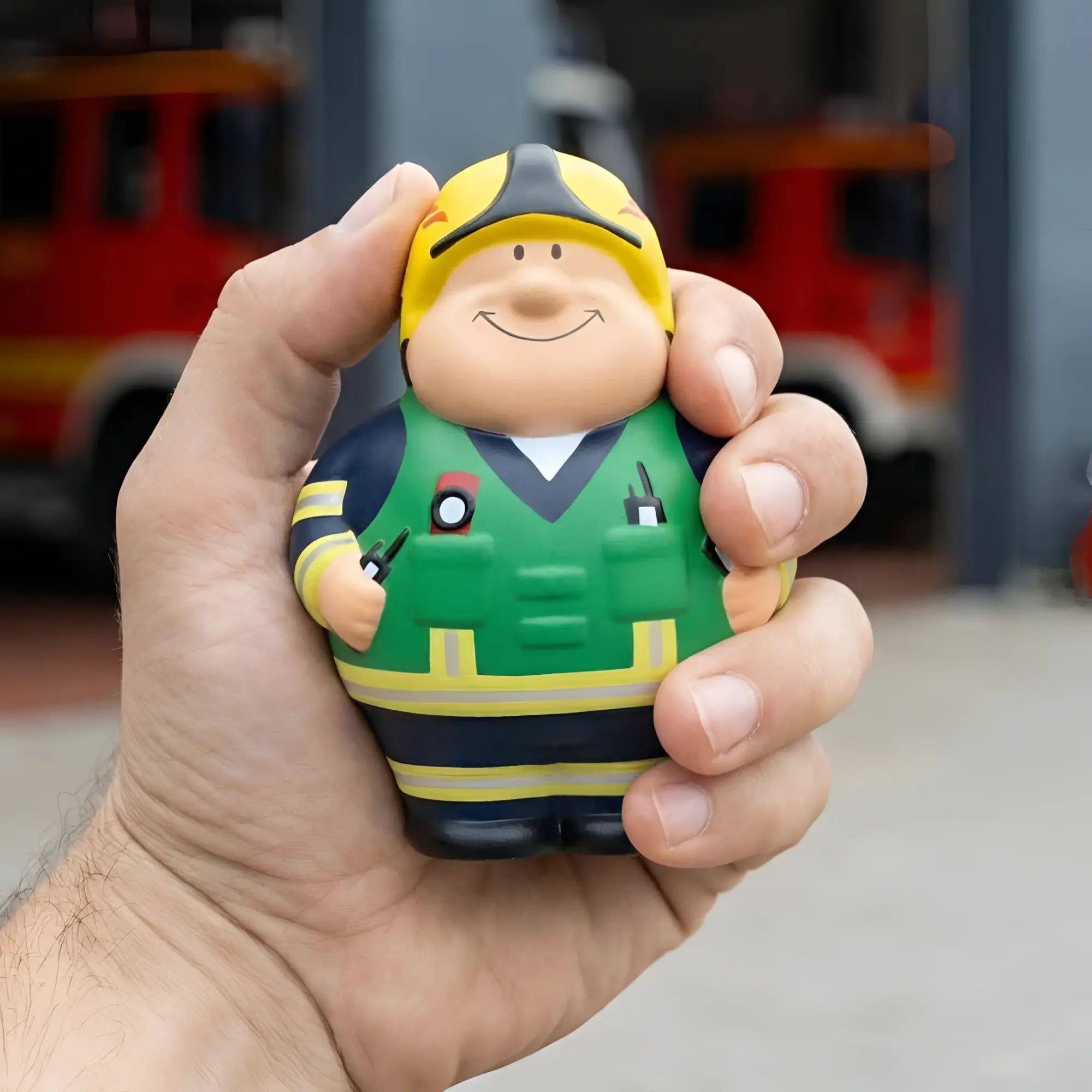 Ein fröhlicher feuer bert 2.0 stressball feuerwehrmann mit gelbem helm grün schwarzer uniform zum knautschen