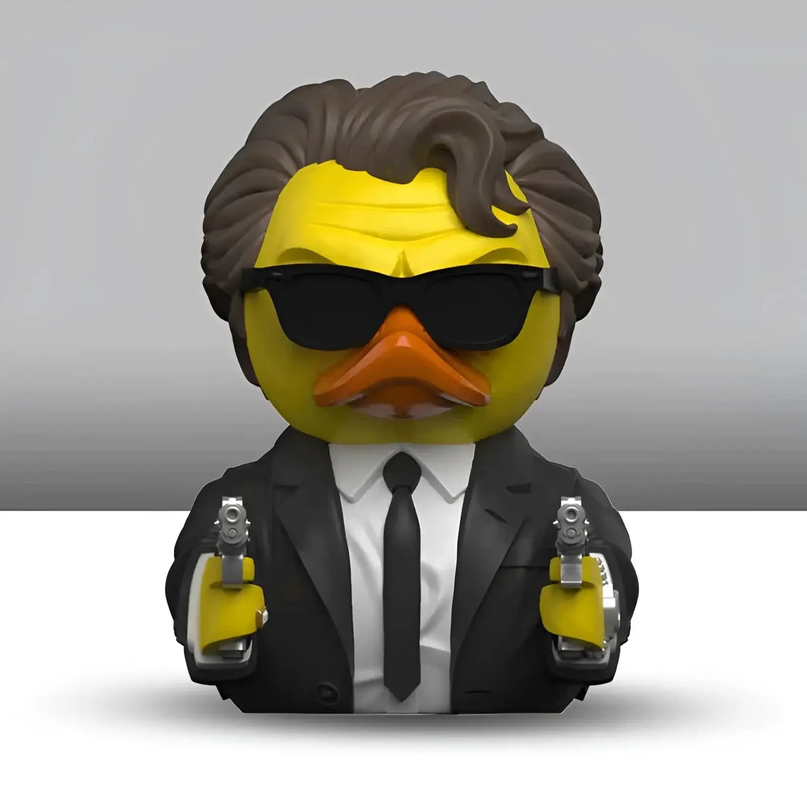 Gelbe badeente mit braunen haaren schwarzen sonnenbrillen oranger schnabel schwarzem anzug und zwei silbernen pistolen aus geschenkset reservoir dogs tubbz