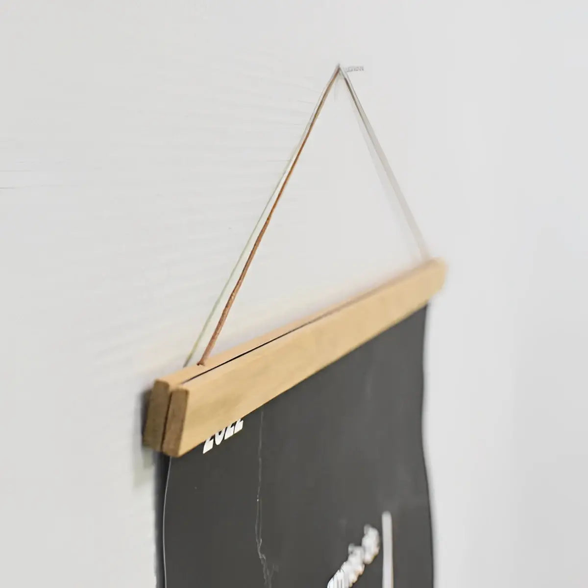 HĂ€ngender magnetrahmen fĂŒr rubbelposter mit minimalistischem holzrahmen in natur und dĂŒnner seilaufhĂ€ngung