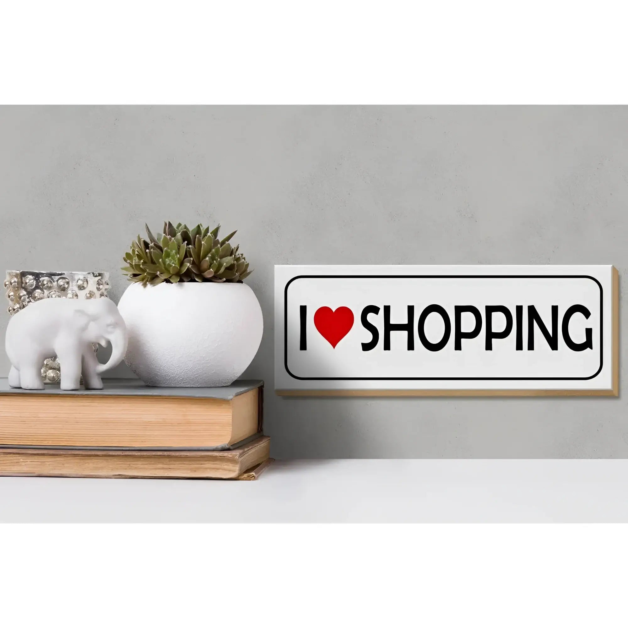 Weißes rechteckiges holzschild mit schwarzem rahmen und dem spruch i herz shopping in schwarzer schrift mit rotem herz