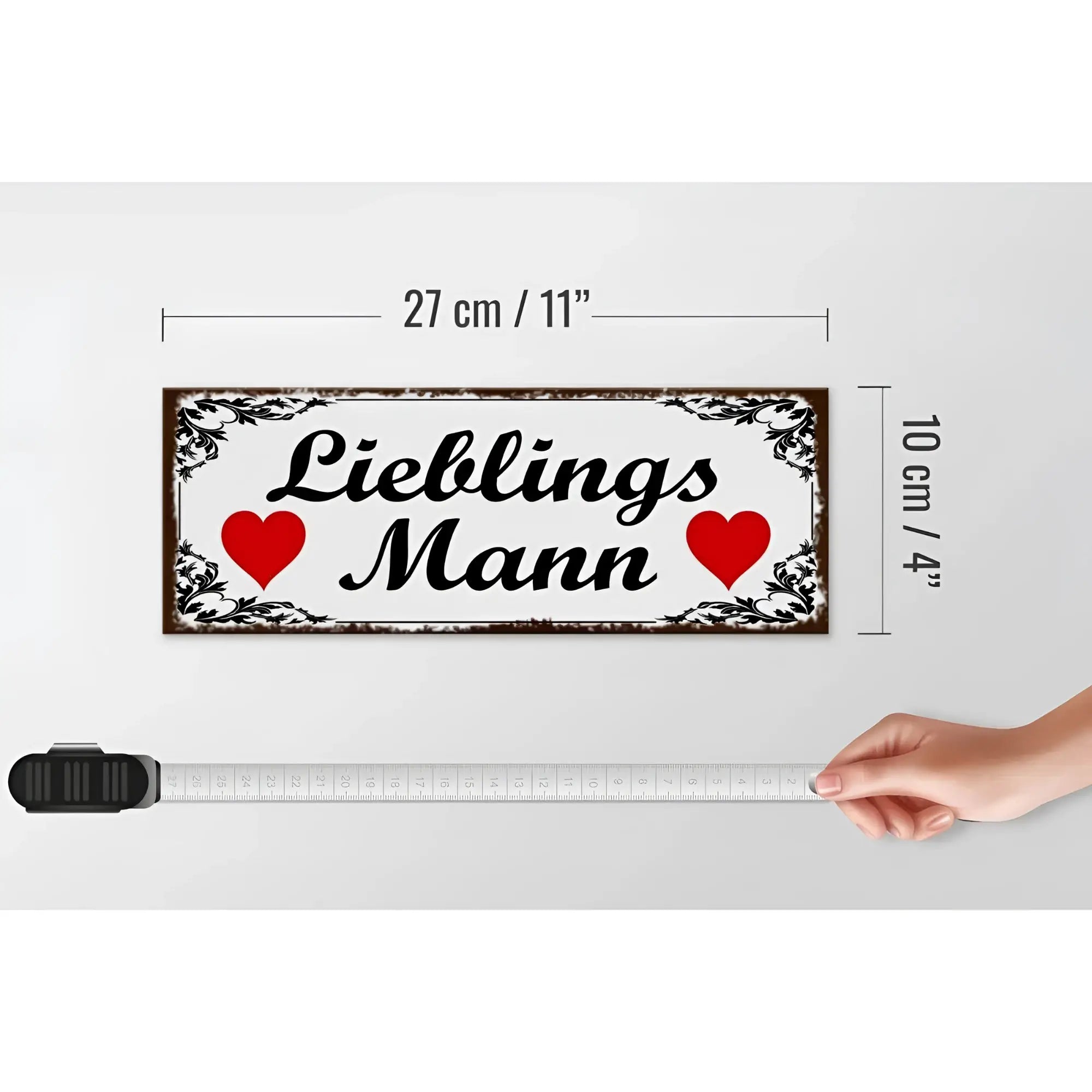 Weißes metal holzschild 27x10cm mit schwarzem ornament rahmen und lieblingsmann schriftzug zwischen zwei roten herzen