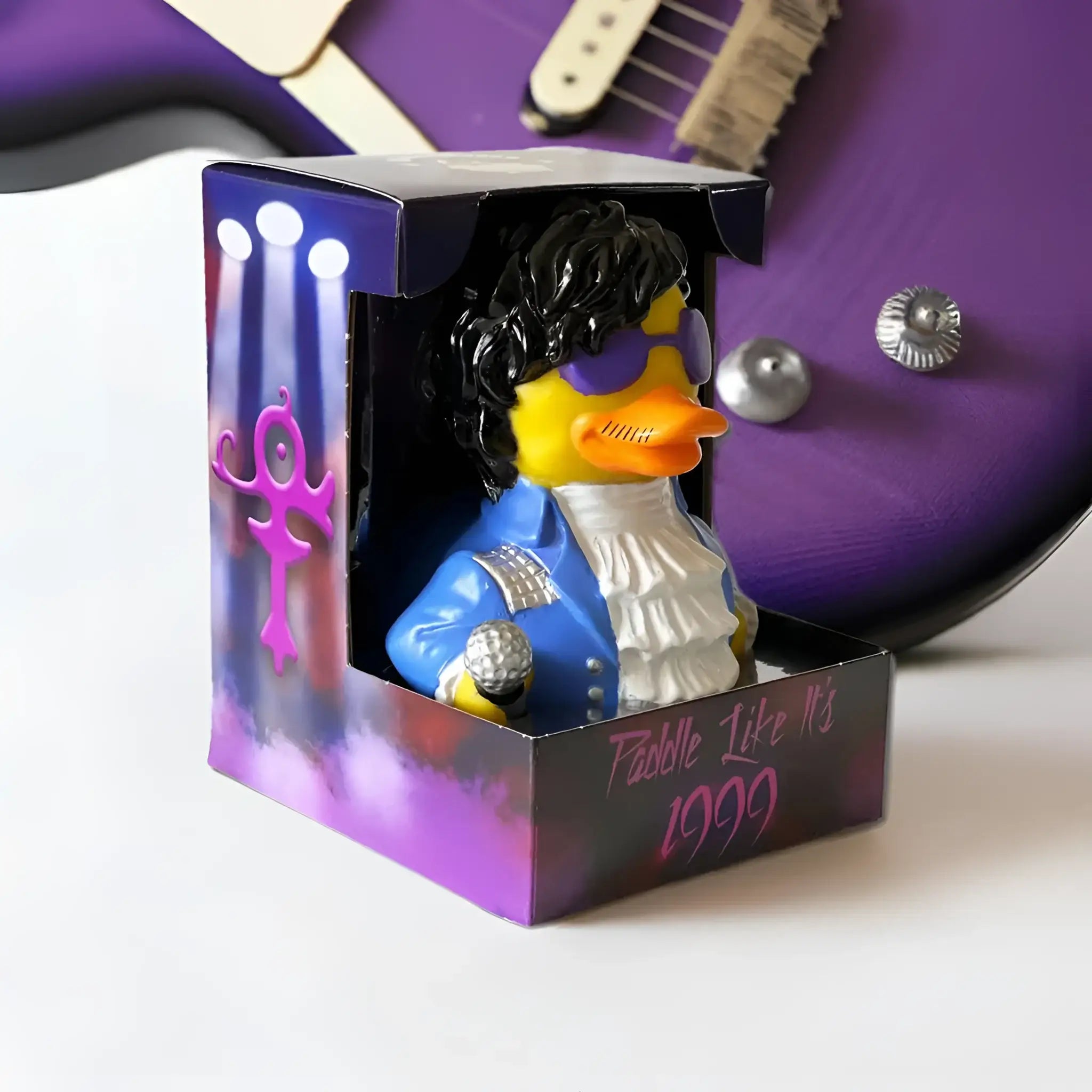 Lila und blaue gummiente als prinz mit schwarzer lockiger perücke und silbernem mikrofon von celebri ducks