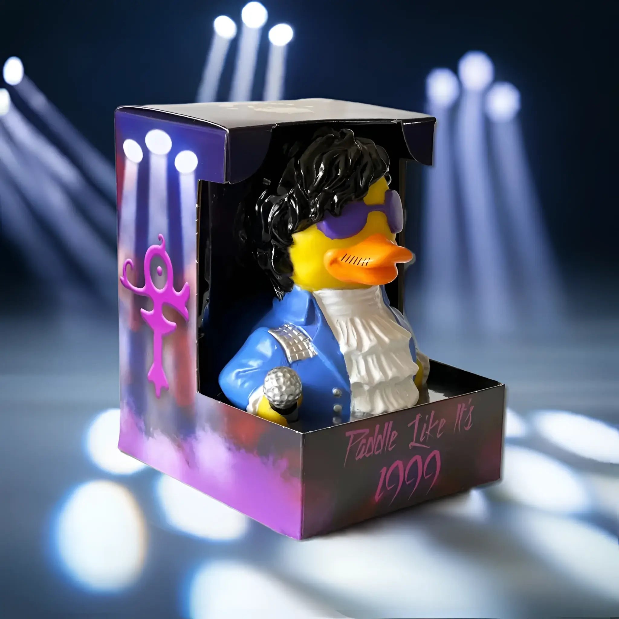 Eine gelbe gummiente als prince mit schwarzer lockiger haarpracht, lila sonnenbrille, blauer jacke und mikrofon von celebriducks