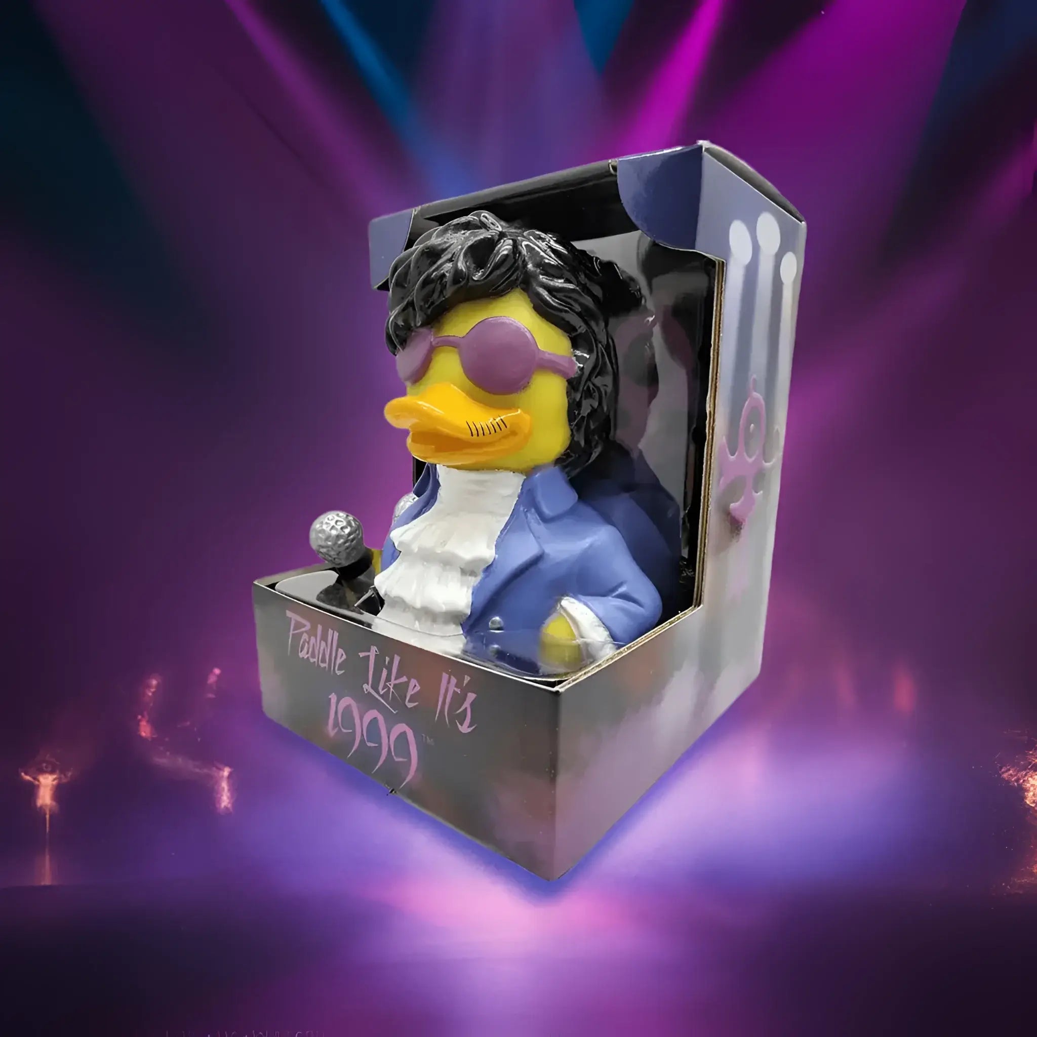 Gelbe gummiente als prinz mit schwarzer lockiger perücke, lila sonnenbrille, blauer jacke und silbernem mikrofon von celebriDucks