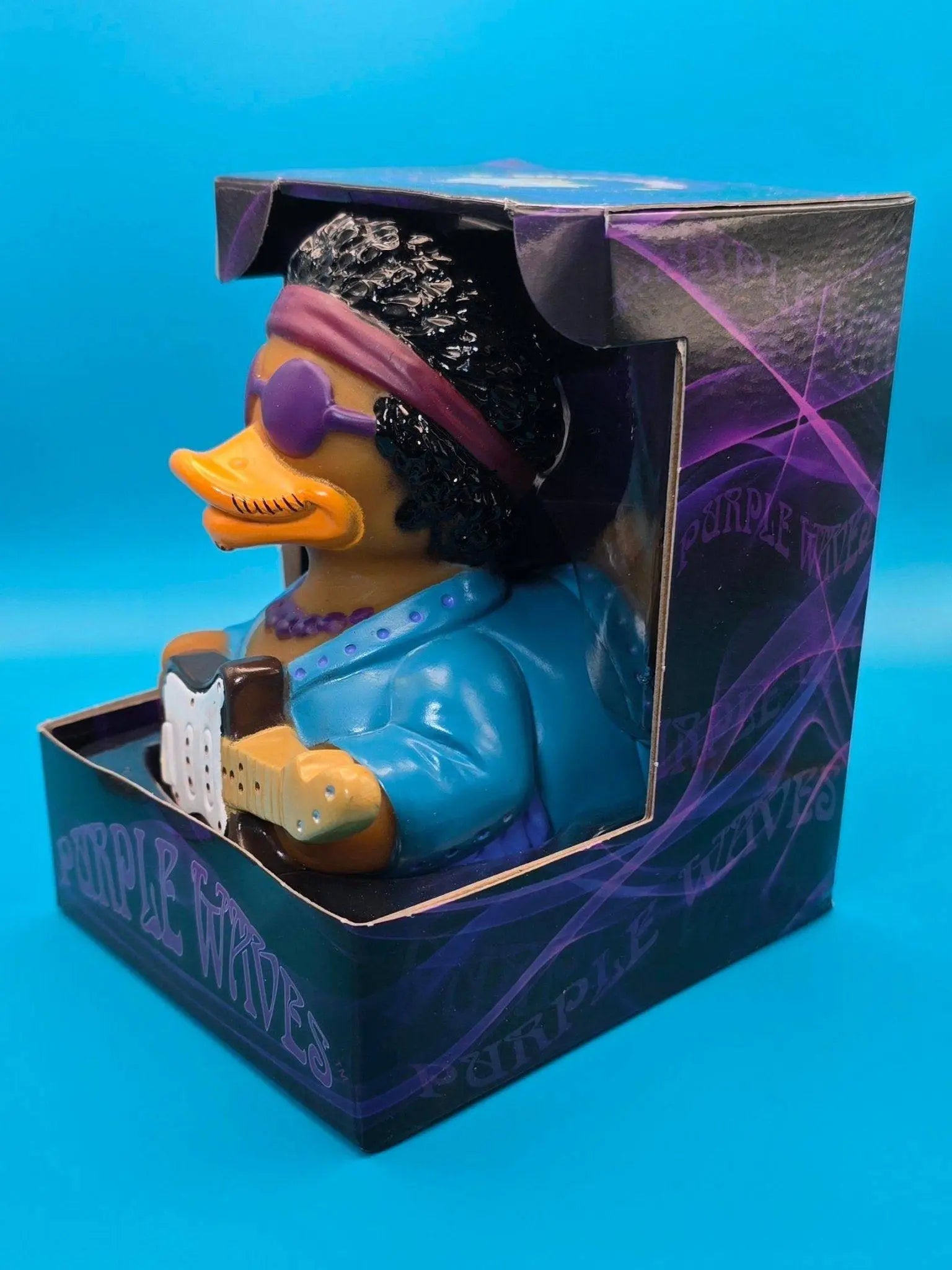 Ein lila wellen gummiente von celebriducks als rockstar mit schwarzer lockiger haarpracht und e-gitarre