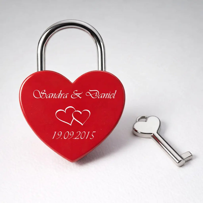 Rotes herzförmiges schloss mit silberner gravur von namen und datum und passendem silbernen schlüssel gravierte geschenke