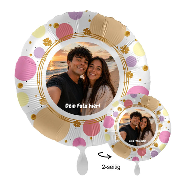 Ein personalisierbarer Fotoballon mit weißer Basis, rosa, gelben und goldenen Punkten und floralen Akzenten um das bedruckte Bild von zwei lächelnden Personen.
