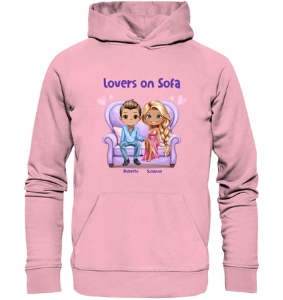 Pink hooded sweatshirt mit cartoon grafik von zwei figuren auf sofa und text lovers on sofa personalisierbar