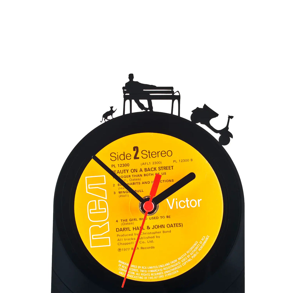 Schallplattentischuhr dolce vita aus schwarzem vinyl mit gelbem label und schwarzen silhouette-motiven von bank und motorrad