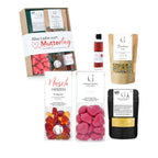 Ein geschenkset alles liebe zum muttertag mit einer box, rosa herzbonbons, roter flasche, kräutern und kaffeebechern