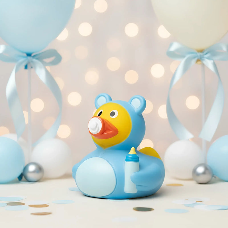 Blaue gummiente mit gelbem gesicht und oranger schnauze hält babyflasche babyshower badeente für neugeborene