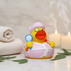 Eine gelbe quietsche-ente mit rosa bademantel und duschkappe hält einen spiegel und roten lippenstift