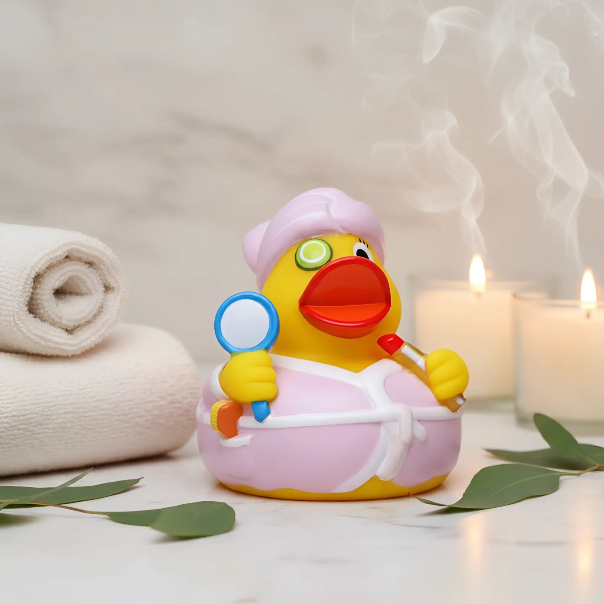 Eine gelbe quietsche-ente mit rosa bademantel und duschkappe hält einen spiegel und roten lippenstift