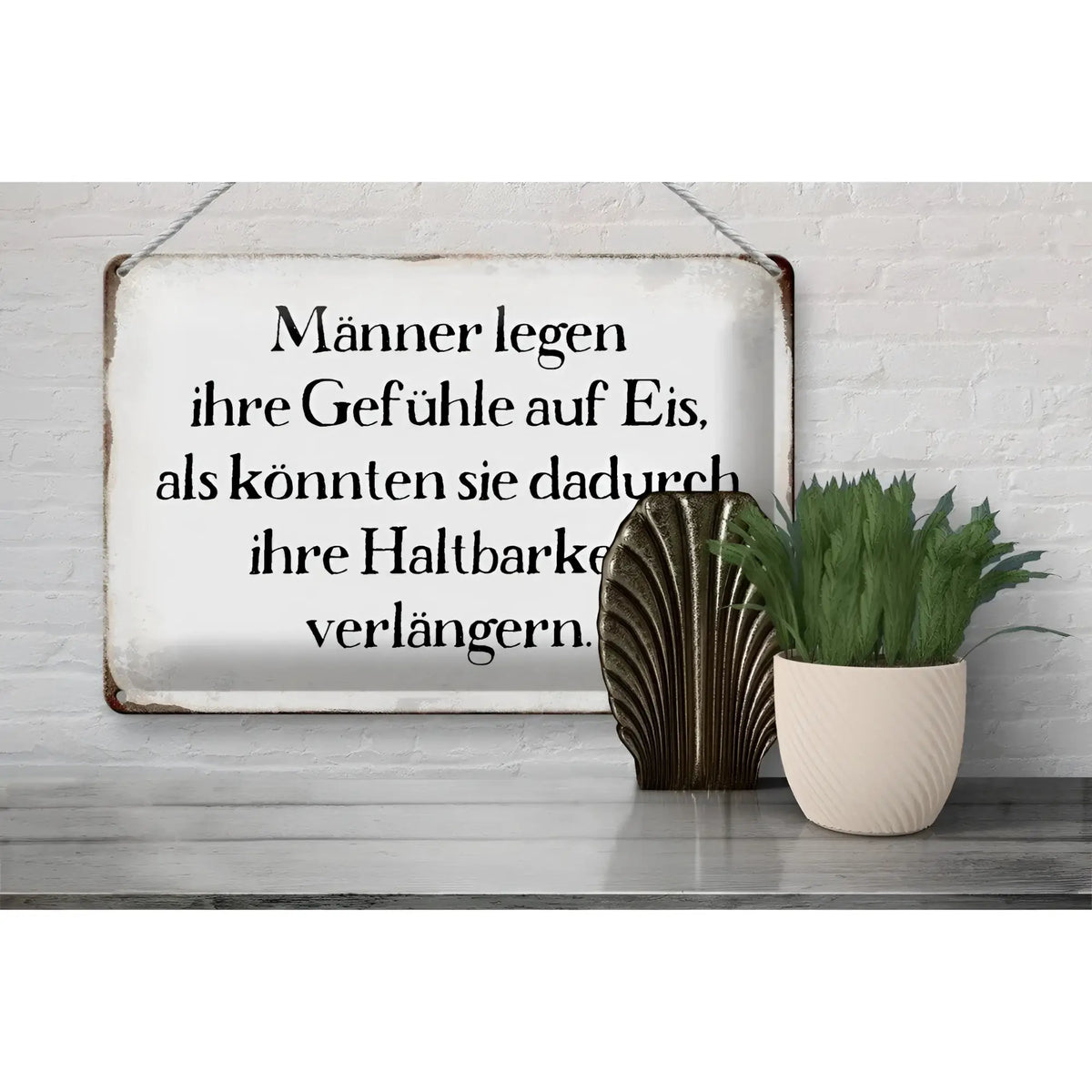 Weißes rechteckiges blechschild mit schwarzem spruch männer legen gefühle auf eis und rostigen kanten an weißer wand