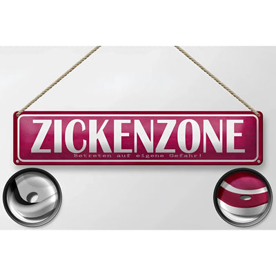 Ein maroonfarbenes blechschild 46x10 cm aus metall mit weißer aufschrift zickenzone eigene gefahr zum aufhängen