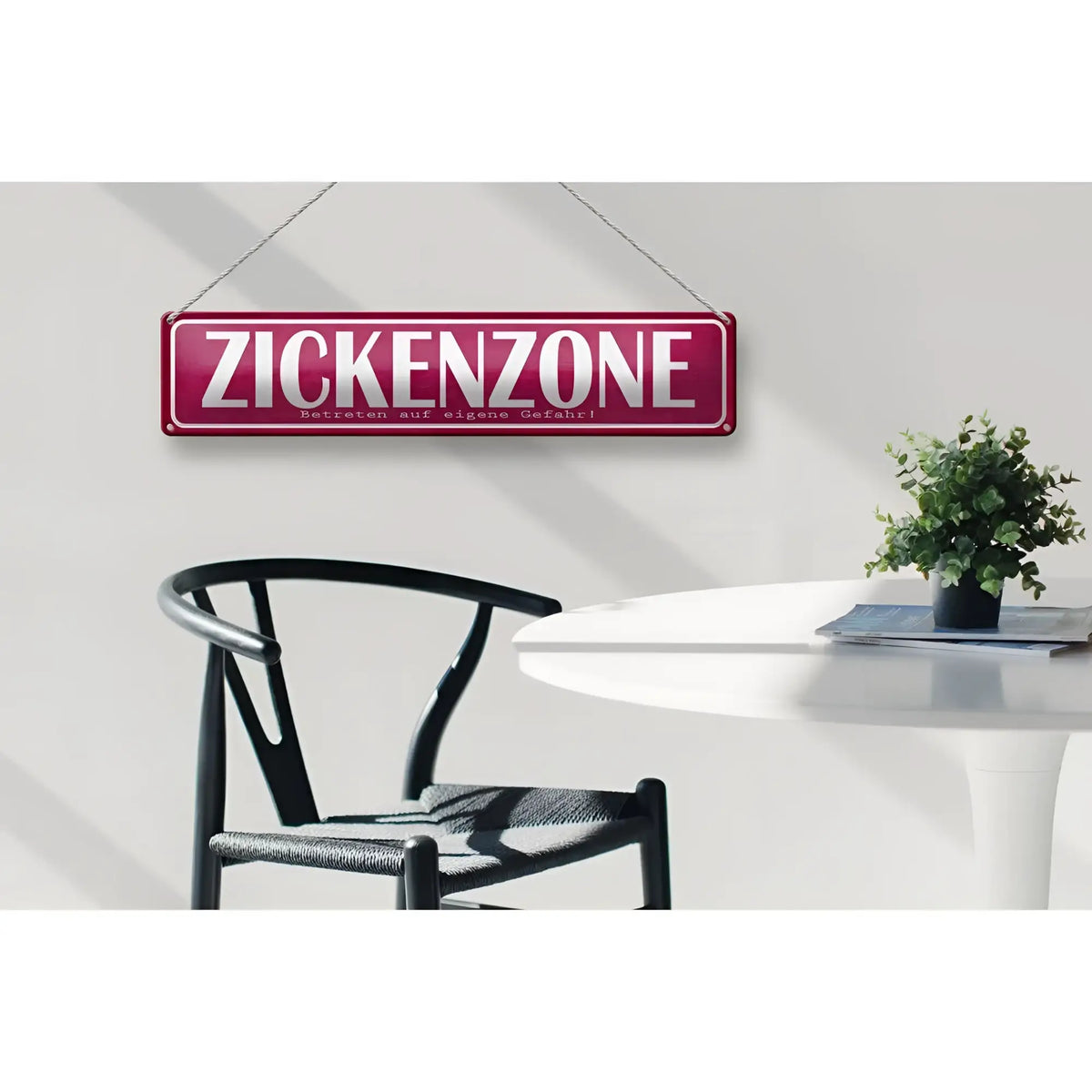 Ein maroonfarbenes rechteckiges blechschild aus metall mit weißer aufschrift zickenzone und ketten zum aufhängen