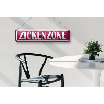 Ein maroonfarbenes rechteckiges blechschild aus metall mit weißer aufschrift zickenzone und ketten zum aufhängen