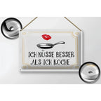 Weisses rechteckiges blechschild 30x20cm mit schwarzem spruch ich küsse besser als ich koche und bratenpfanne, lippenstiftspuren