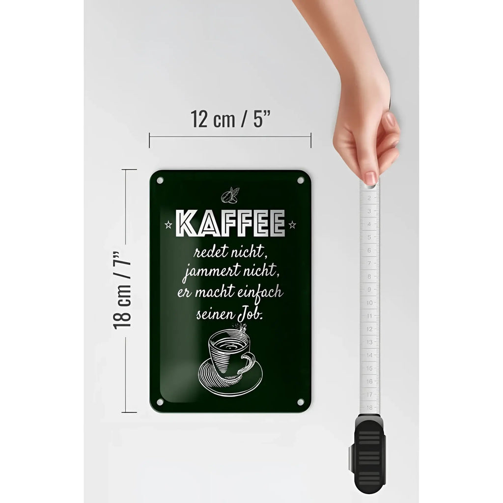 Dunkelgrünes rechteckiges blechschild mit weißem eingraviertem spruch kaffe jammert nicht macht job und kaffeetasse