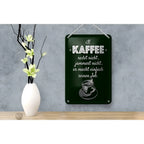 Dunkelgrünes rechteckiges blechschild mit weiß graviertem spruch kaffe jammert nicht job und kaffeeillustration am seil hängend