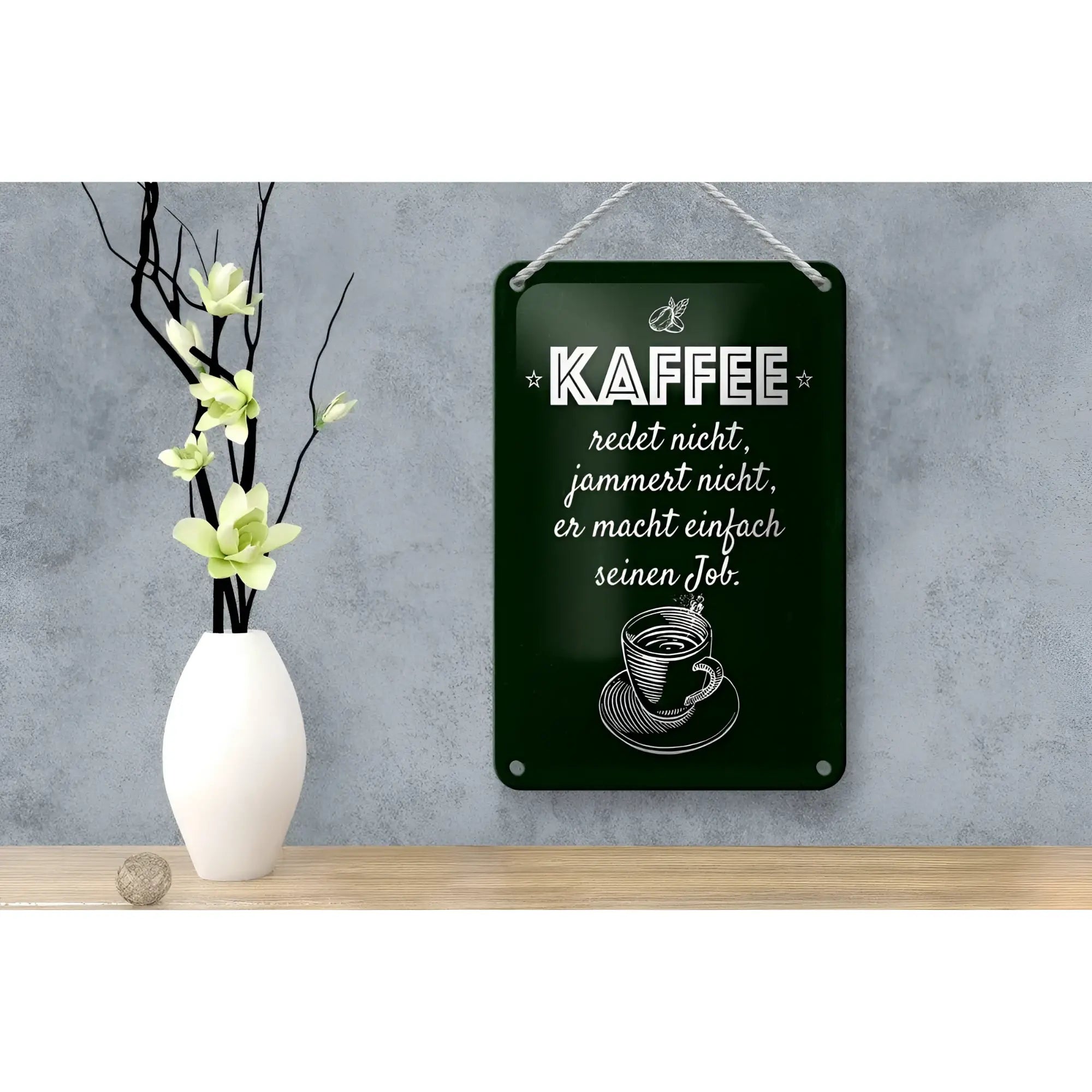 Dunkelgrünes rechteckiges blechschild mit weiß graviertem spruch kaffe jammert nicht job und kaffeeillustration am seil hängend