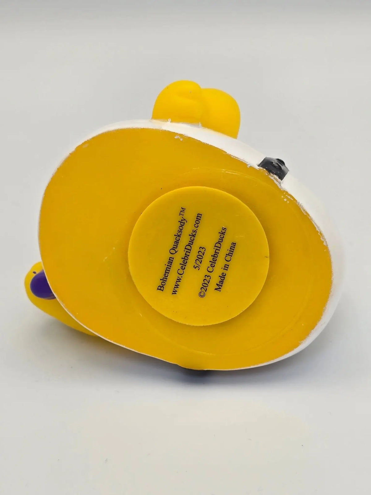 Gelbe und weiße gummiente bohemian quacksody mit rundem label auf der rückseite von celebriducks