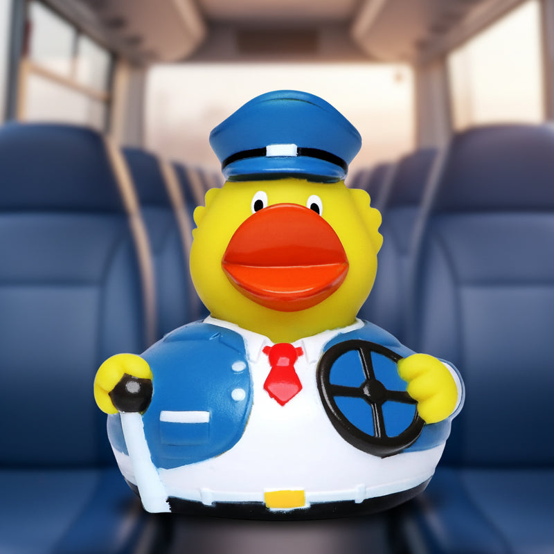 Gelbe quietscheente als busfahrer in blauer uniform mit roter krawatte hält ein lenkrad aus gummi