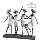Silberfarbene kunstharz skulptur von vier stylisierten frauen mit hüten die sich an den händen halten auf dunklem sockel