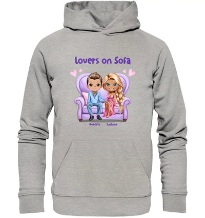 Grauer kapuzenpullover mit cartoonmotiv von zwei figuren auf lila sofa und text lovers on sofa aus statement-collection