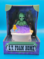Grüner alien gummiente im weißen bad mit lila schaum gelber badeente und ufovorm spielzeug von celebriducks