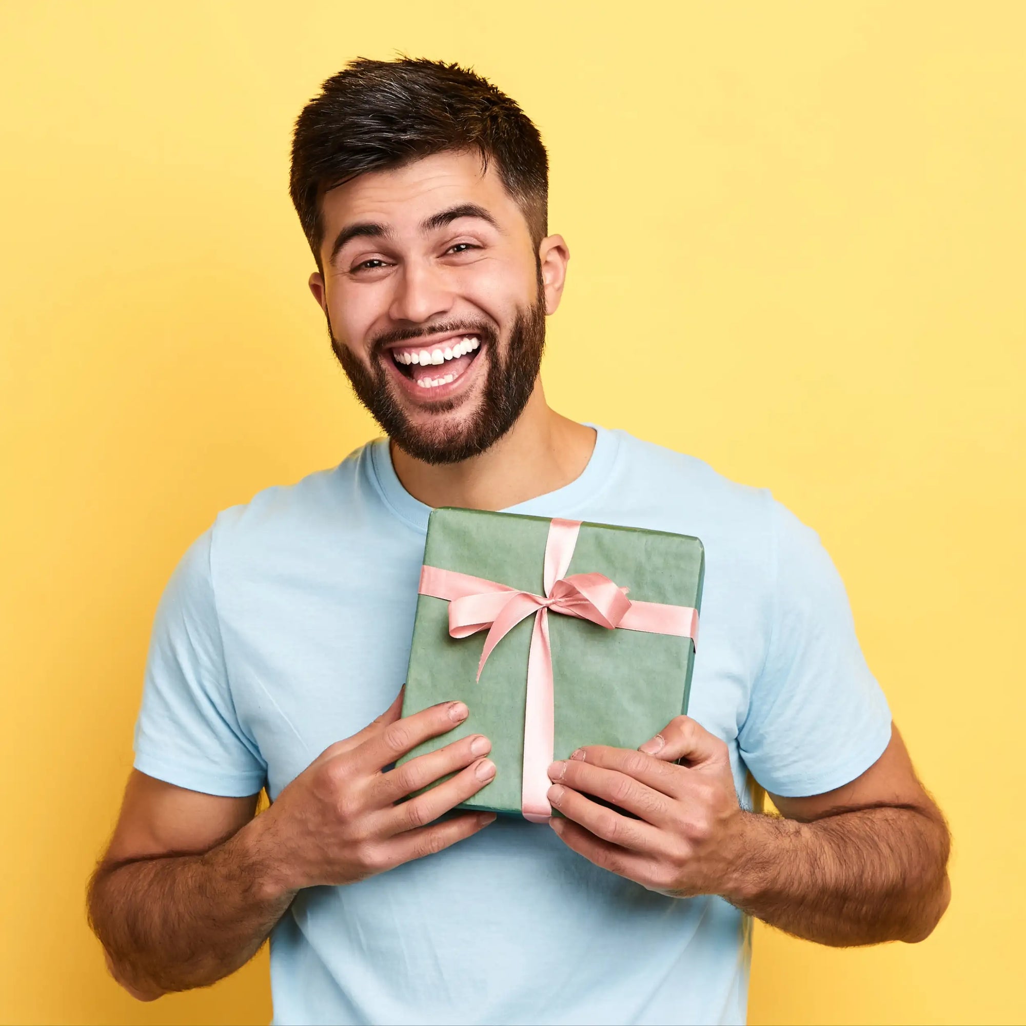 Eine grüne Geschenkbox, verpackt mit einer zarten pinkfarbenen Schleife.