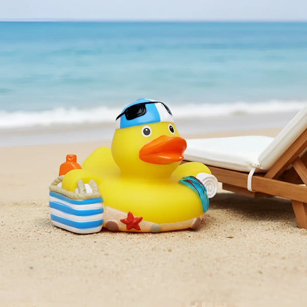 Eine gelbe quietsche-ente mit blau-weiß gestreifter badekappe schwarzbrille und handtuch für strand sommerurlaub