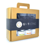 Goldfarbenes gin tasting geschenkset mit schwarzem band und drei kleinen ginflaschen durch klare fenster sichtbar