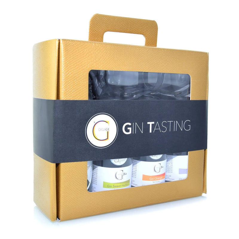 Goldfarbenes gin tasting geschenkset mit schwarzem band und drei kleinen ginflaschen durch klare fenster sichtbar