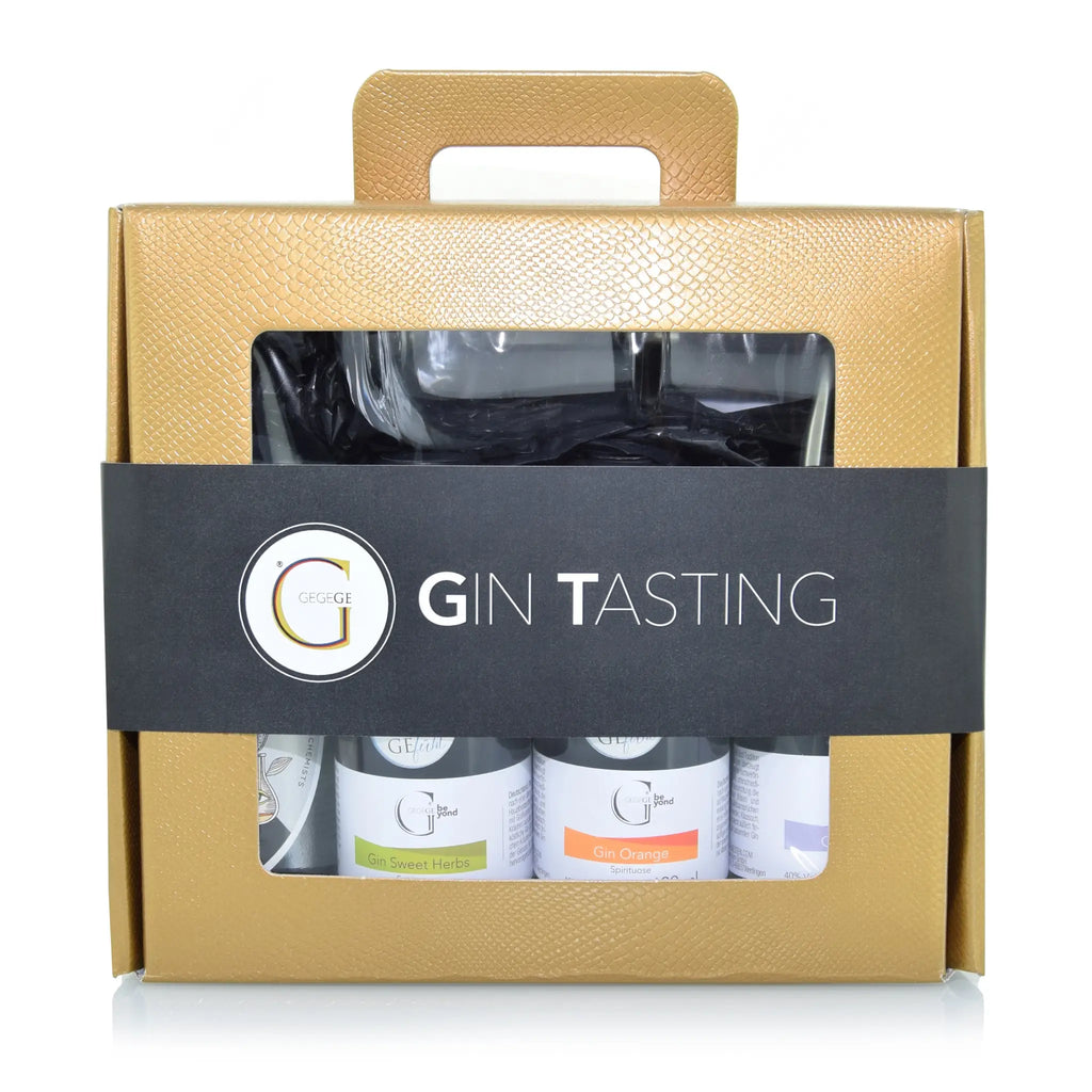 Gold strukturierte geschenkbox mit schwarzem band gin tasting mit drei kleinen flaschen und glas fürs probieren