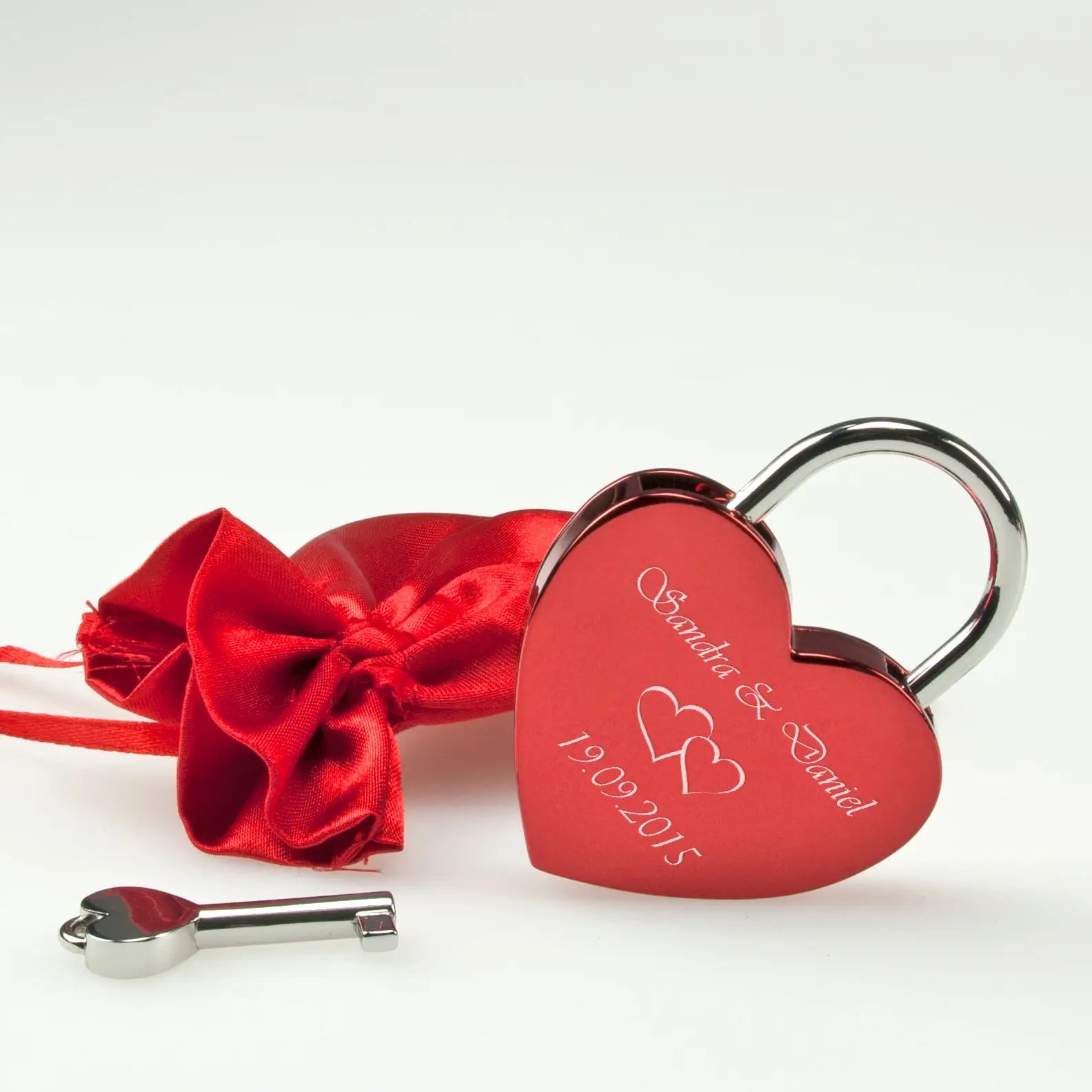Rotes herz vorhängeschloss mit silberner symbolgravur und passendem schlüssel in rotem satin beutel