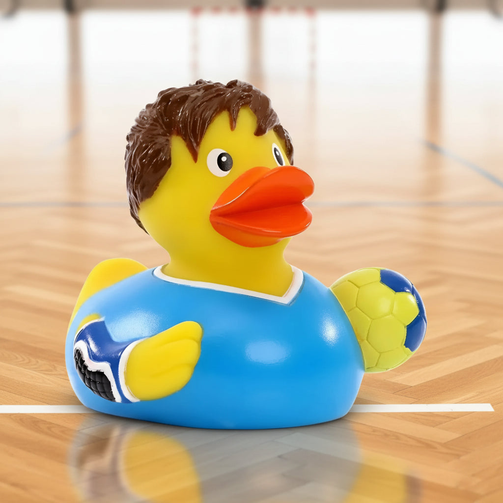 Gelbe Quietsche-Ente mit braunen Haaren, blauem Fußballtrikot und gelb-blauem Ball für Handballspaß