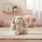 A weiches cremefarbenes plüschtier hase martha mit langen schlappen ohren und oeko-tex-zertifikat sitzt auf teppich