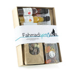 Ein beige karton geschenkset fahrradspaß mit drei kleinen olivenölflaschen und schokolade sowie gummy candies