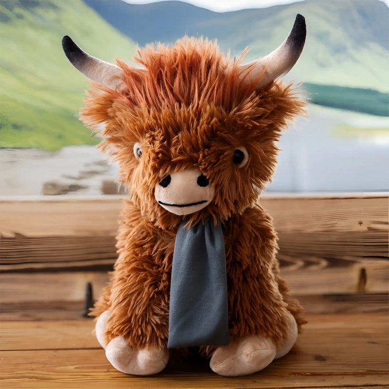 A plush hochlandrind bobby with shaggy brown fur black-tipped horns and a gray scarf soft and cuddly