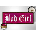 Leuchtendes magentafarbenes holzschild mit weißer gothic beschriftung bad girl und used look als wanddeko 27x10cm