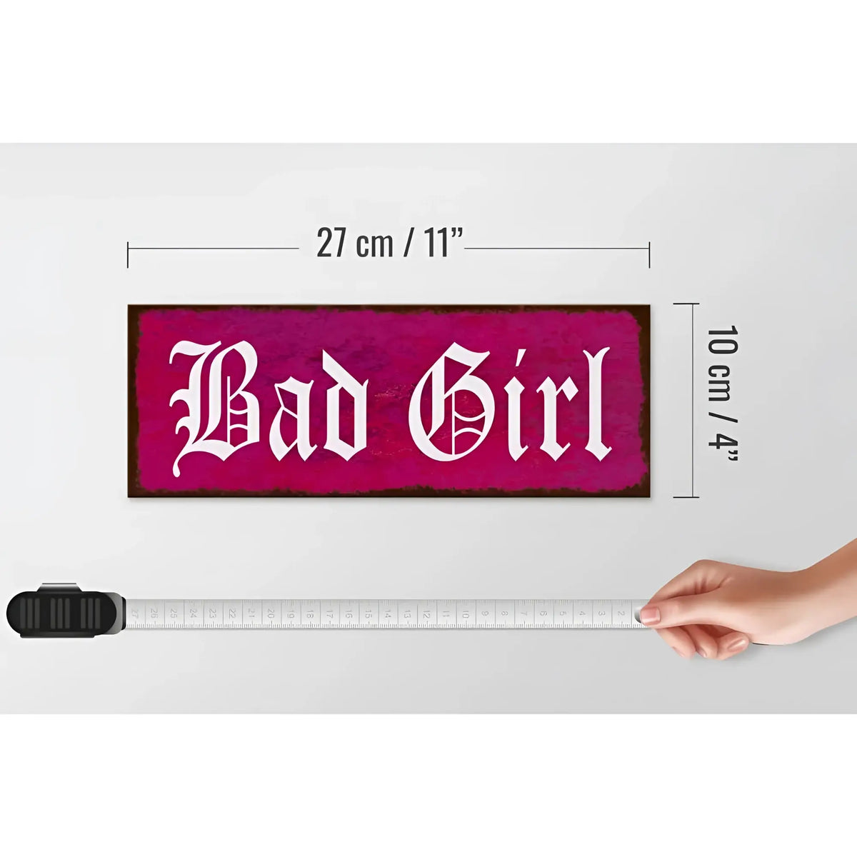 Ein rechteckiges pinkes holzschild mit dem weißen spruch bad girl in gotischer schrift für wanddeko