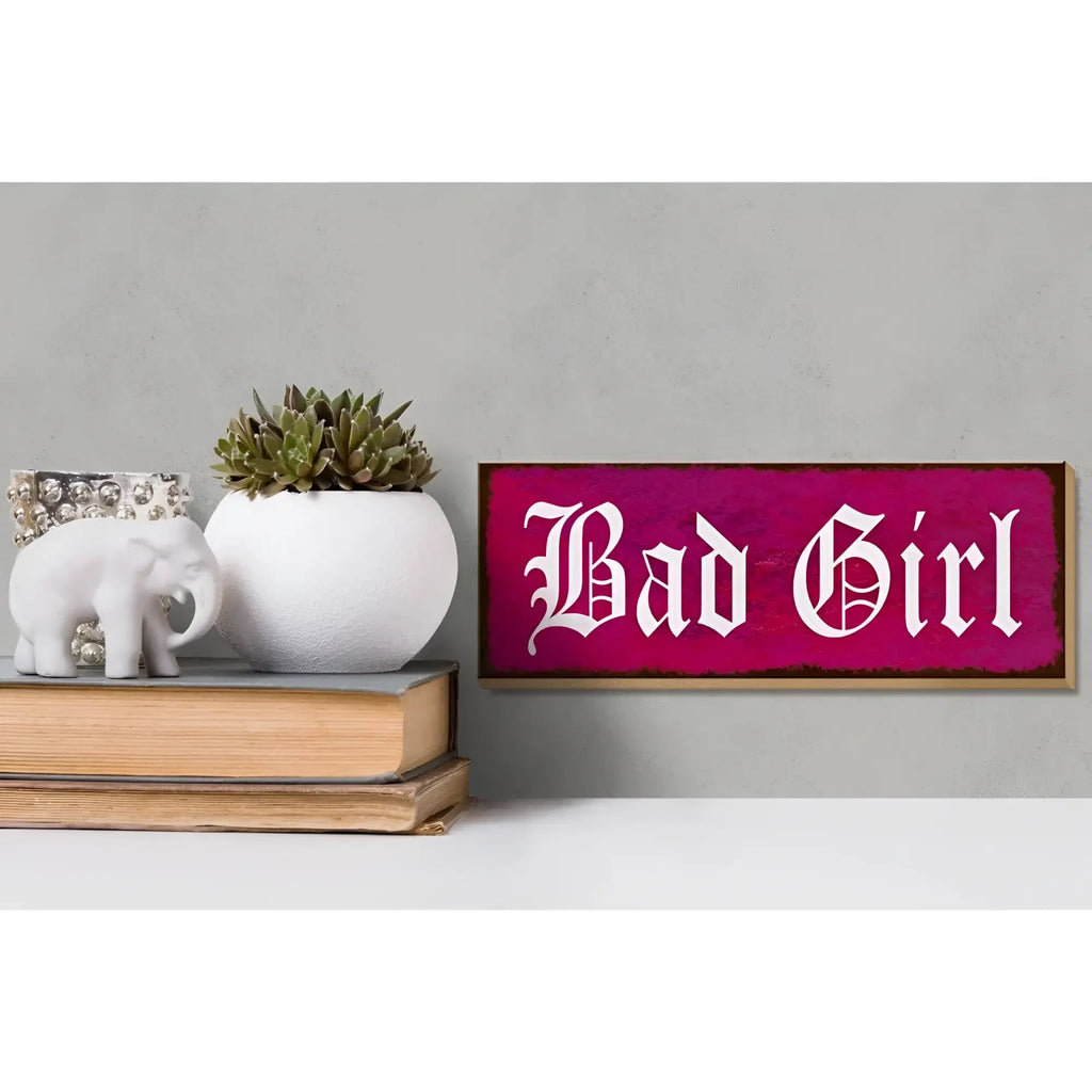 rechteckiges holzschild mit distressed magenta Finish und weißer gotischer schrift bad girl zur wanddeko