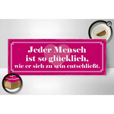Ein pinkes holzschild mit weißem text und herzmotiv mit dem spruch jeder mensch ist so glücklich zur deko