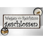 Rechteckiges holzschild mit weißem vintage-look braunem rahmen und schwarzem spruch wegen reichtum geschlossen mit krone