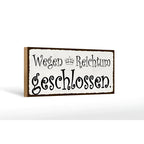 Ein rustikales holzschild 27x10cm mit weißem, distressed look und schwarzer schrift wegen reichtum geschlossen